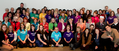 A group photo of Museum staff and volunteers wearing coloured t-shirts.